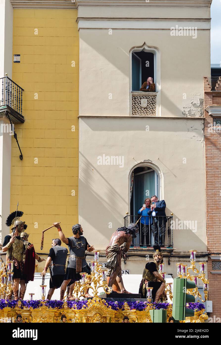 Seville, Spain; April 14, 2022: People watching a procession from their balconies during the Holy Week.  Brotherhood of 'Las Cigarreras' Stock Photo