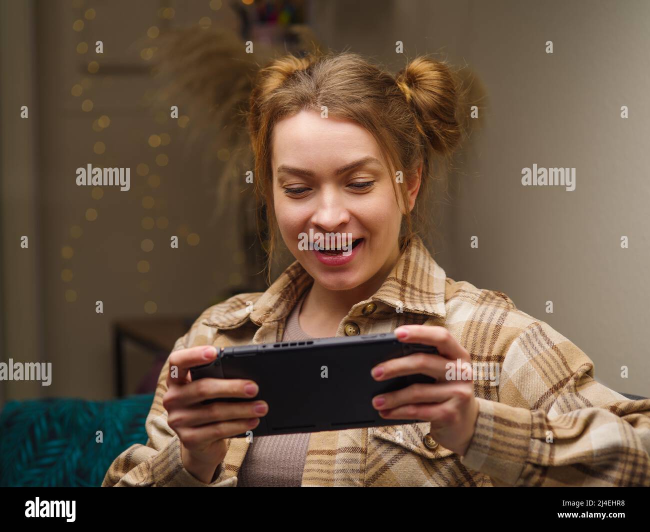 Girl gamer plays a video game on a portable game console. The girl is happy to win. Online games with friends, fun, prizes, wins, virtual reality, new Stock Photo