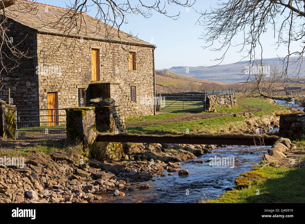 A stone house in Cotterdale, Yorkshire Dales National Park with a narrow bridge over Cotterdale Beck, which eventually flows into the River Ure. Iconi Stock Photo