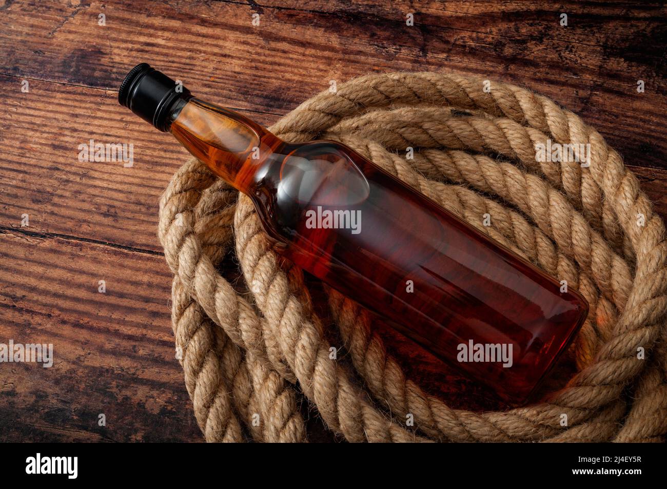 alcoholism in rural america and excessive distilled alcohol and hard liquor drinking concept theme with a bottle of scotch whiskey or brandy and rope Stock Photo
