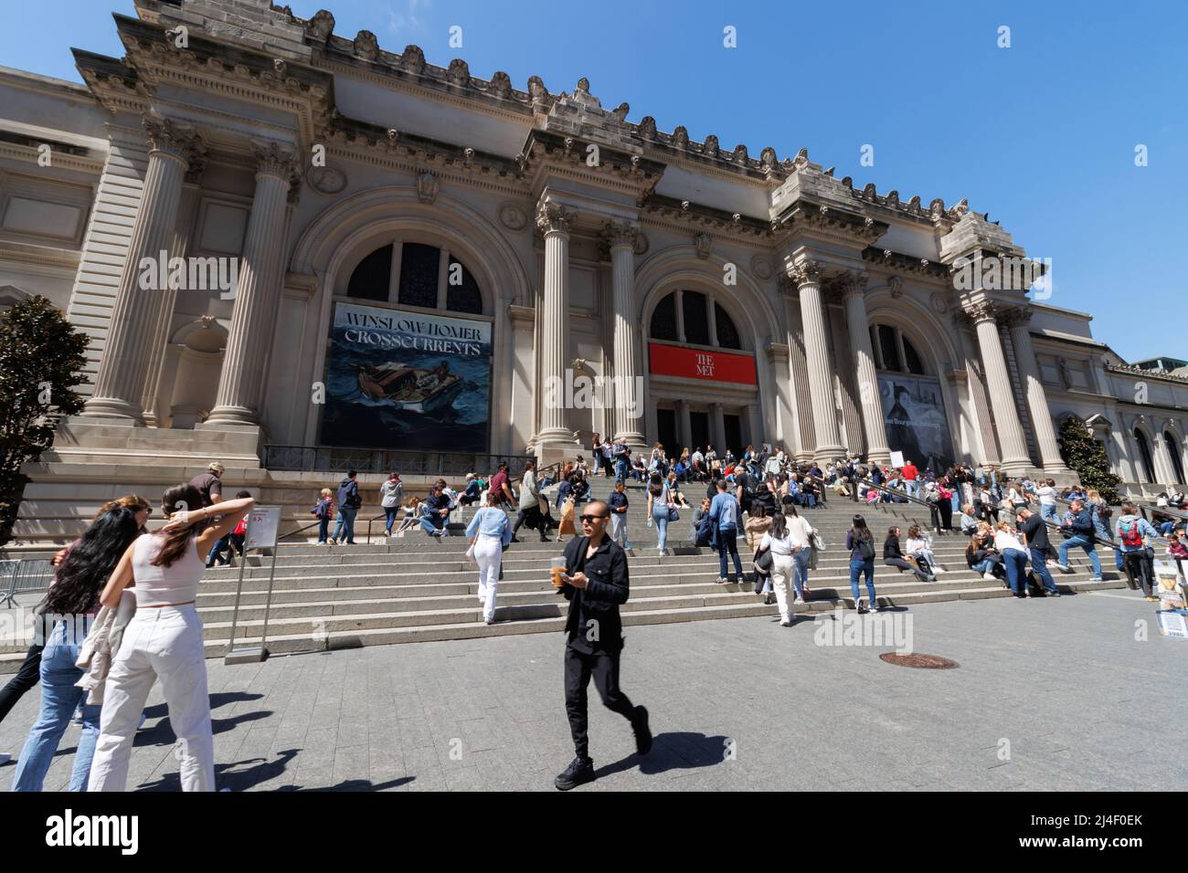 People walk and sit around the grand staircase entrance to the Metropolitan Museum of Art on fifth avenue on a beautiful Spring day Stock Photo