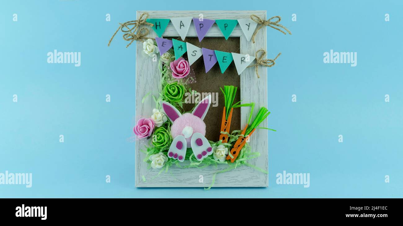 Handmade Creative Easter frame with flowers and cute bunny on blue background Stock Photo