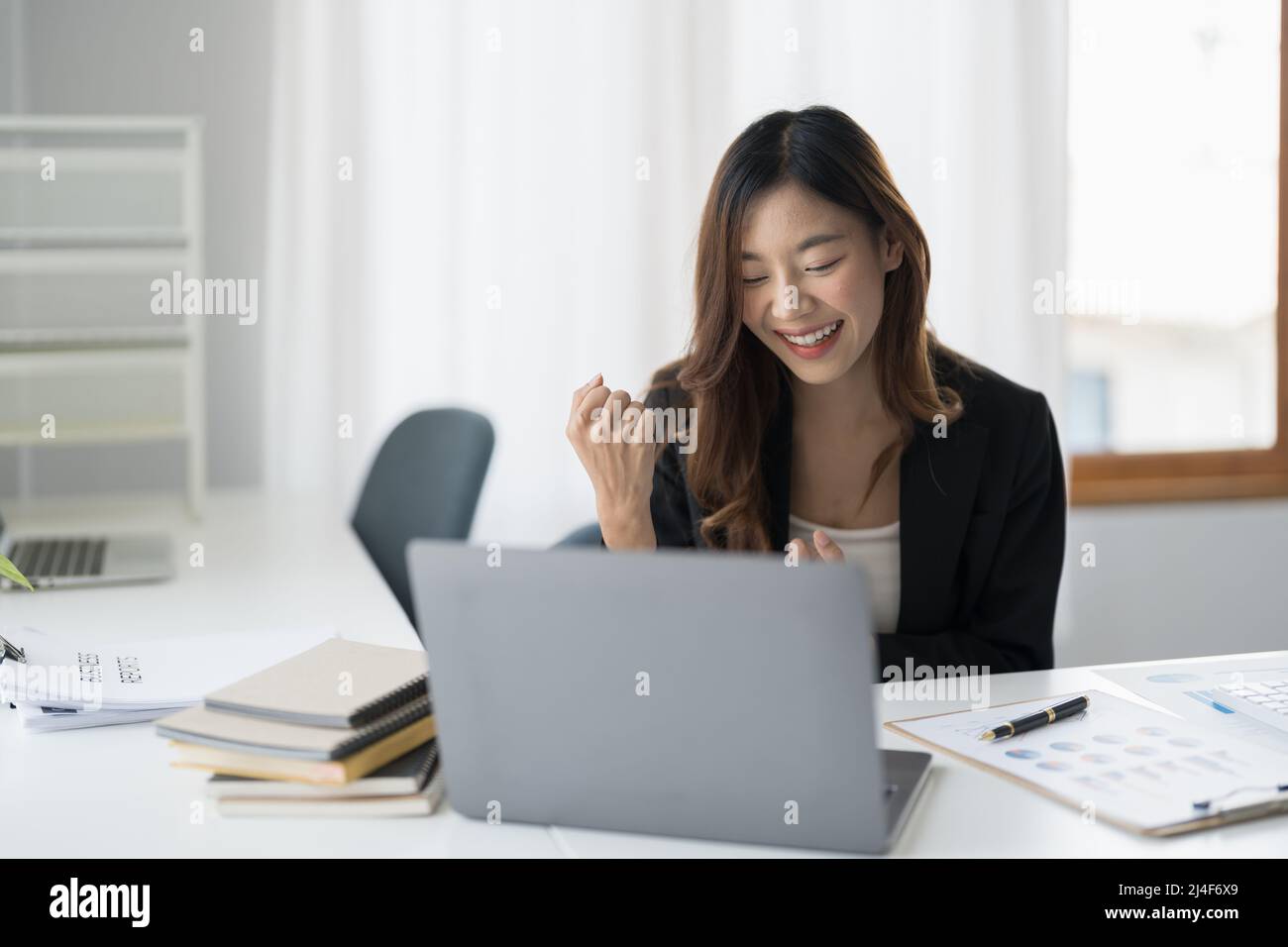 Happy young asian business woman looking at laptop excited by good news ...