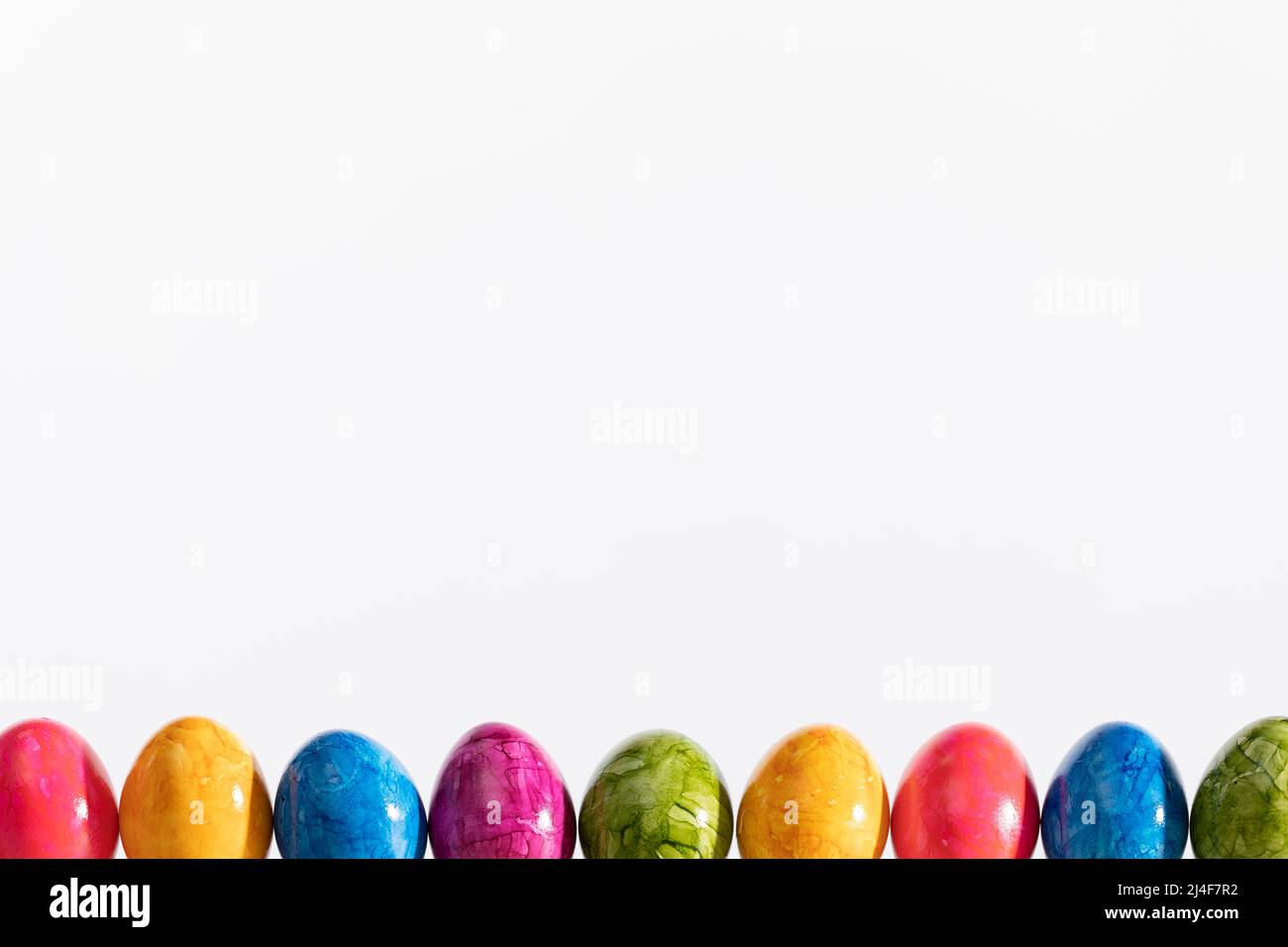 Many Easter eggs arranged in one row on a white background. Easter. Stock Photo