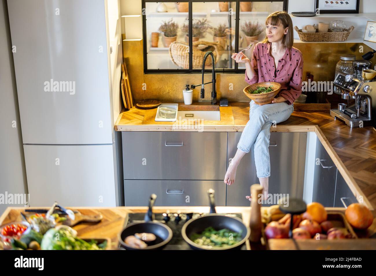 Woman eating salad in modern kitchen at home Stock Photo