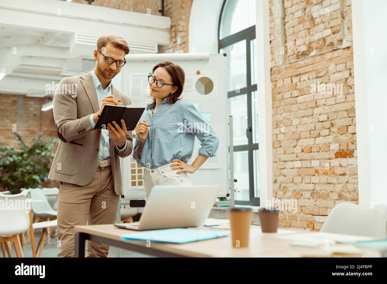 Smiling two colleagues looking at notepad in the office Stock Photo