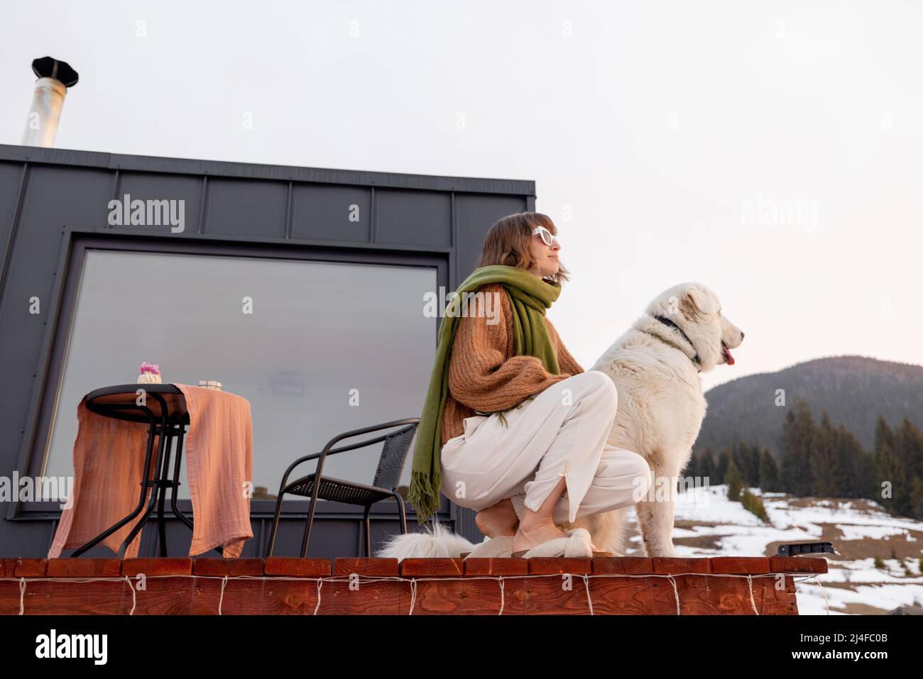 Woman with her dog resting on terrace of tiny house on nature Stock ...