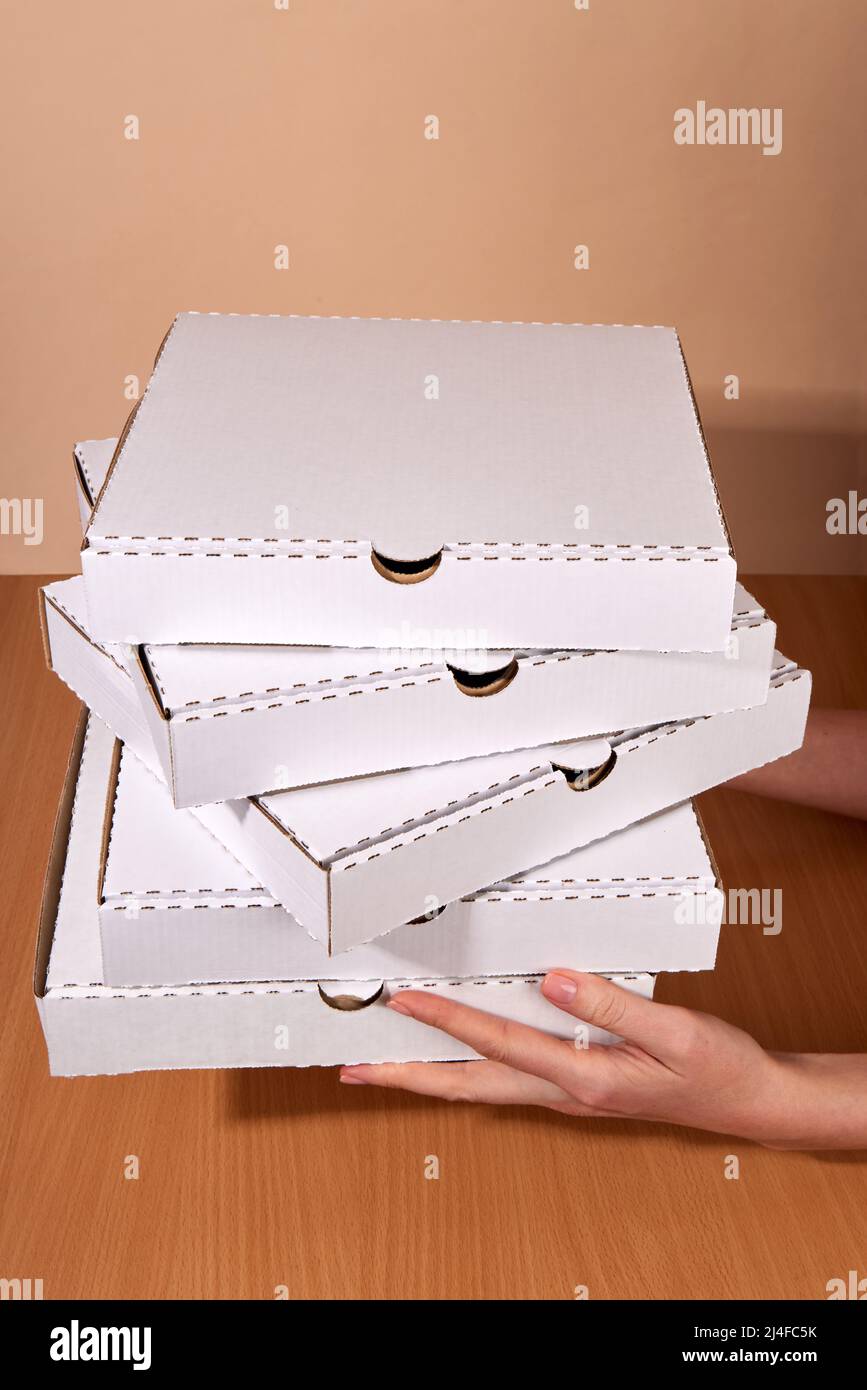 Delivery hands hold cardboard boxes, natural white color, eco-friendly and biodegradable products, boxes for the delivery of food and gifts, confectio Stock Photo