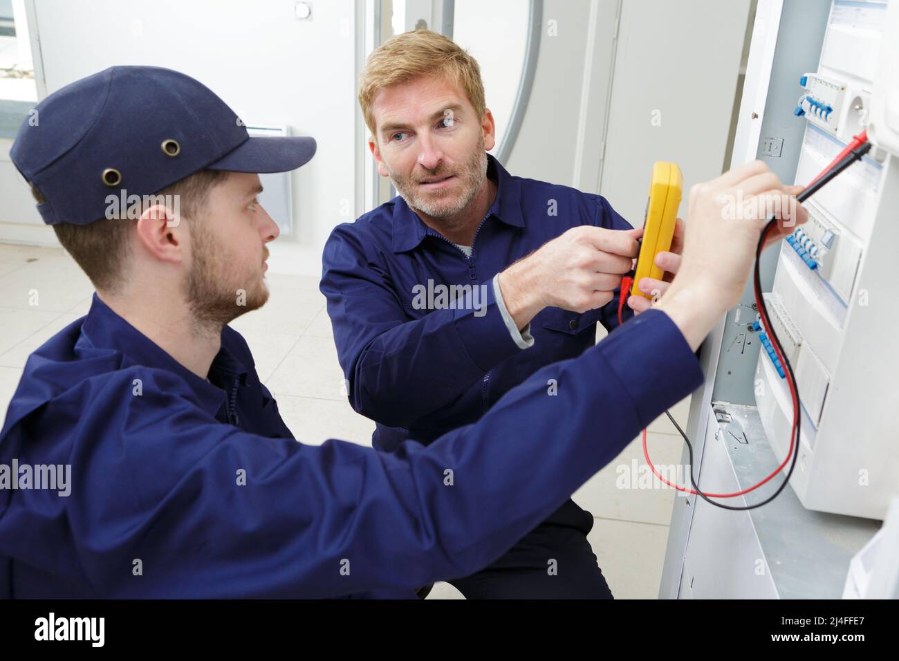 apprentice electrician using a multimeter on a fusebox Stock Photo