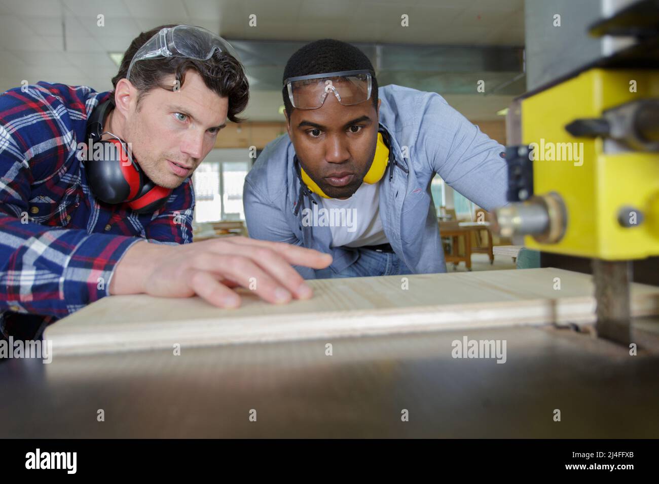 worker with apprentice using band saw Stock Photo