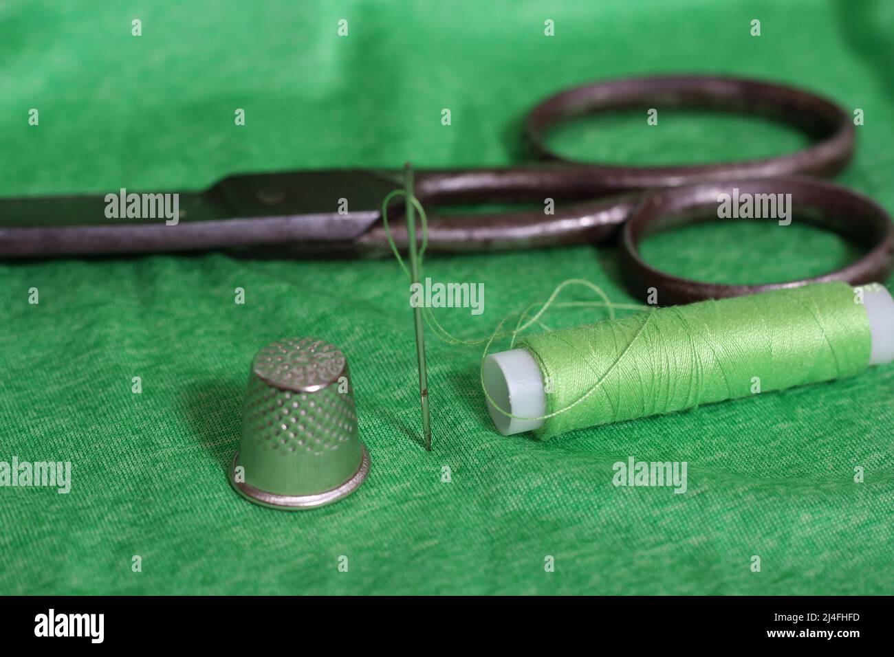 Spool of green thread and needle Stock Photo - Alamy