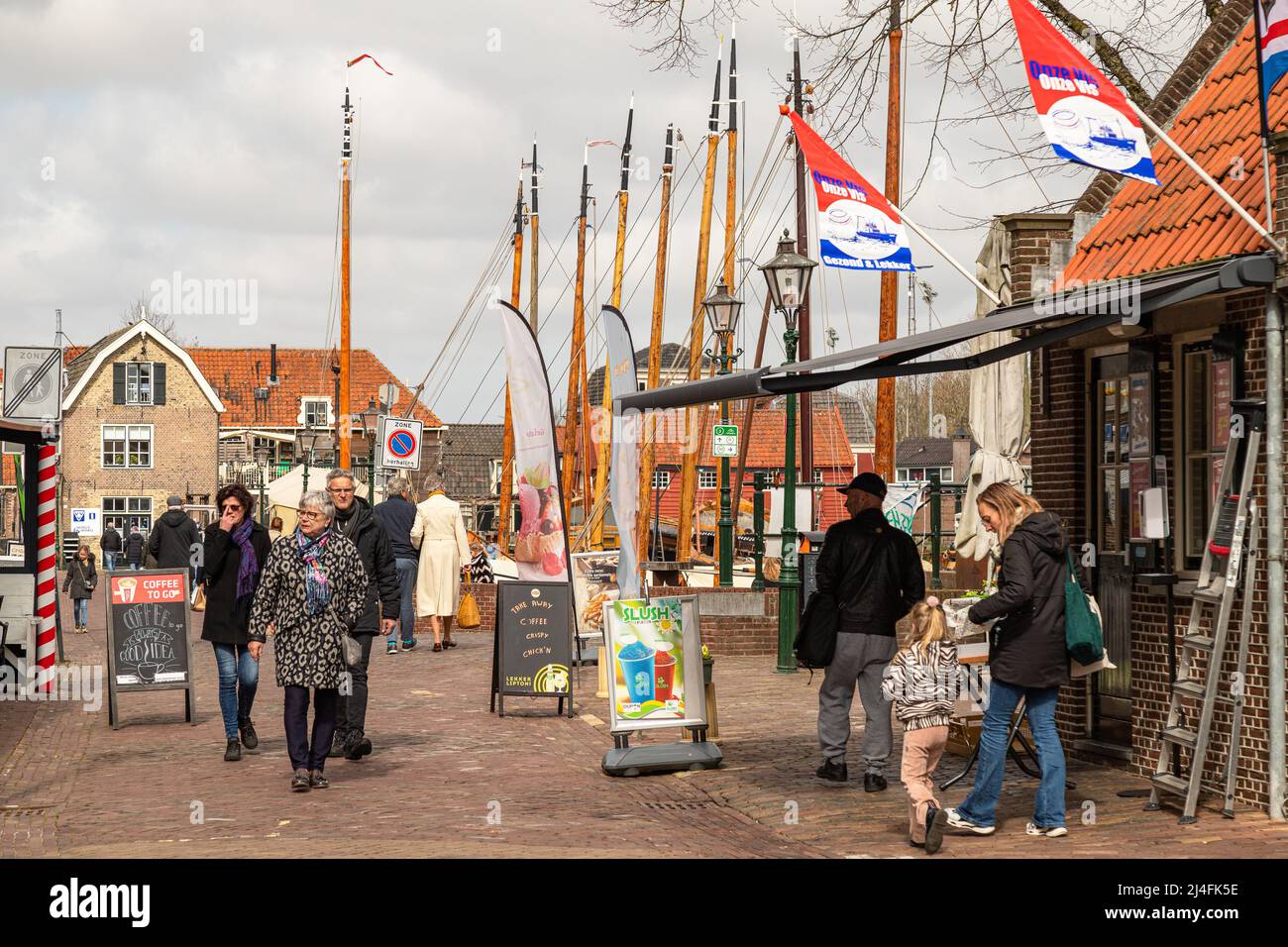 People walk on the quay of the old harbor in the center of the picturesque fishing village of Spakenburg. Stock Photo