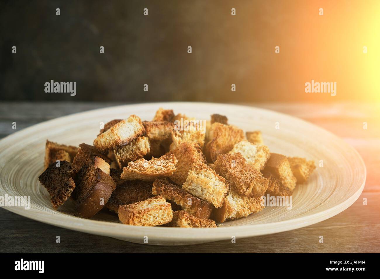Wooden plate with fried breadcrumbs dark background in rays sun. Rustic