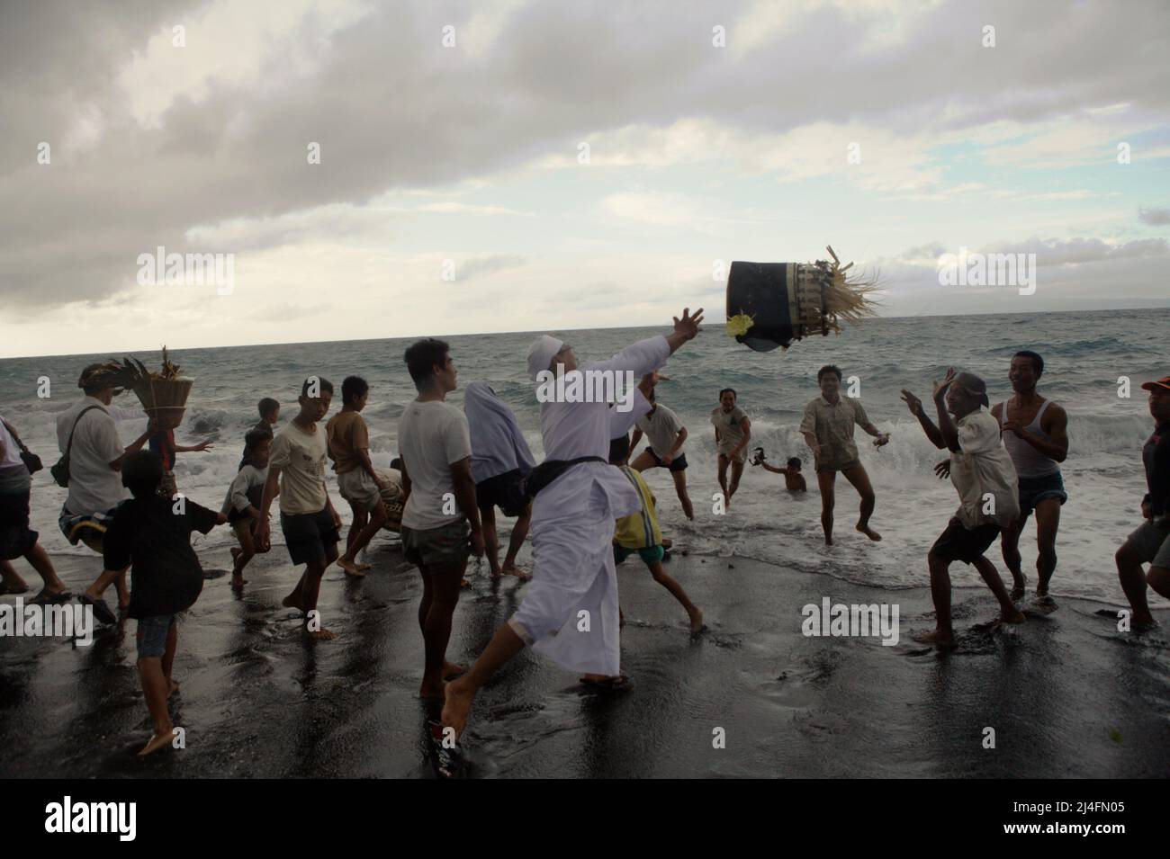 Purifying the spirits: A priest throwing a bucket of offerings during a ...