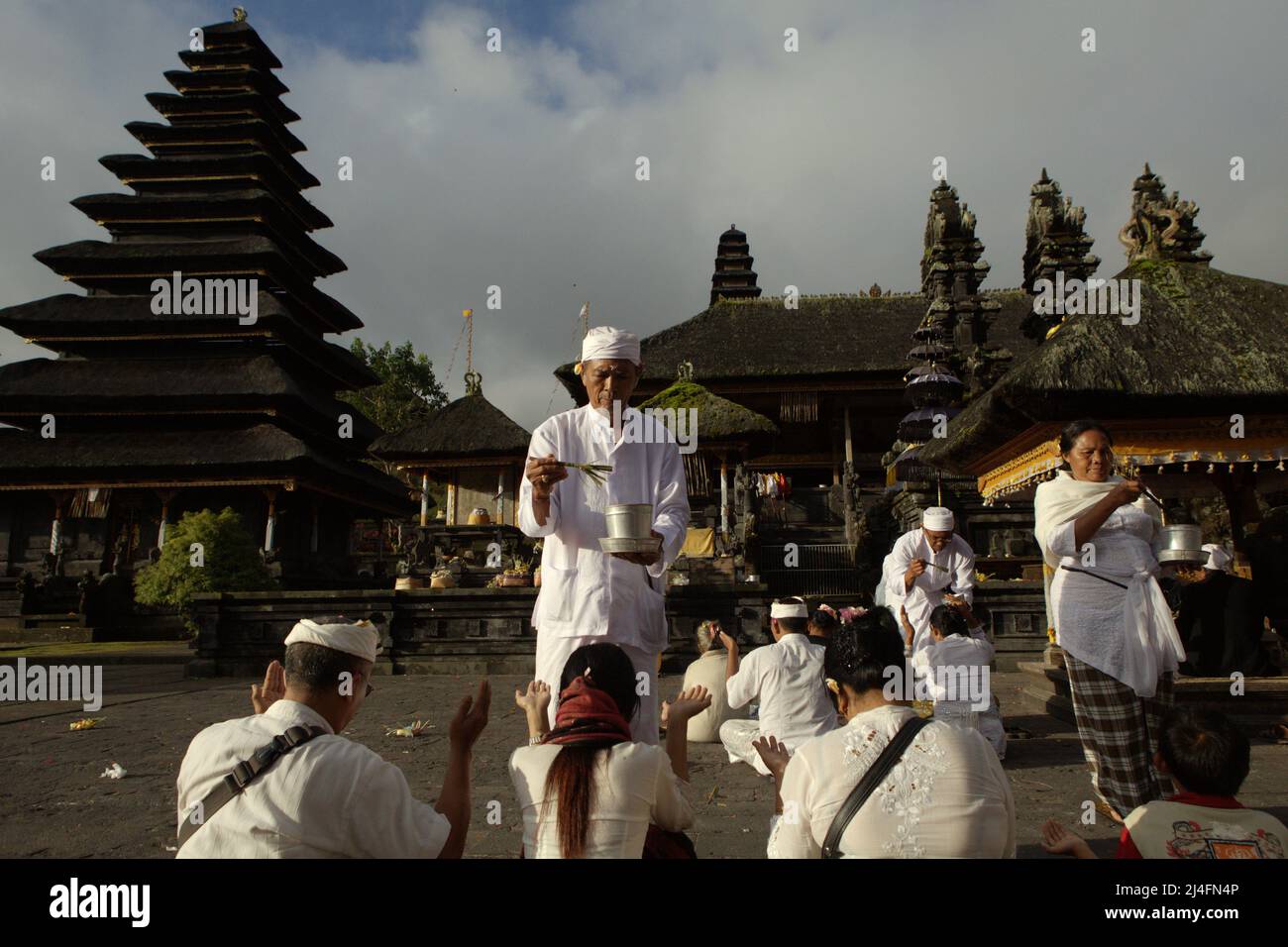 Purifying the spirits: A priest splashing holy water during a Balinese ...