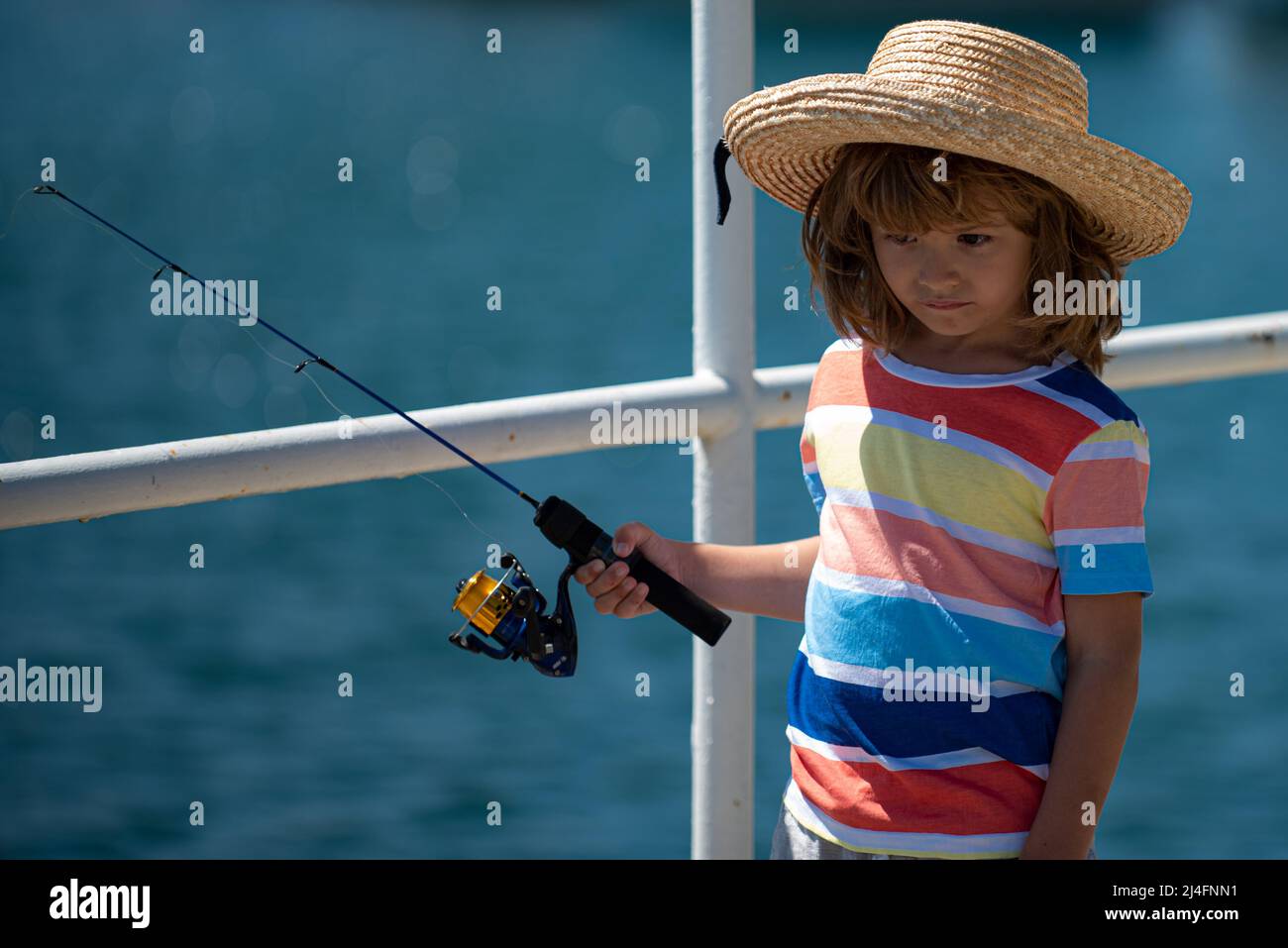 Child boy engaged in fishing hobbies, holds a fishing rod. Summer
