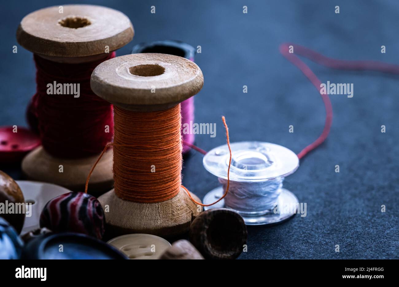 Bobbins of threads standing near buttons and beads Stock Photo Alamy