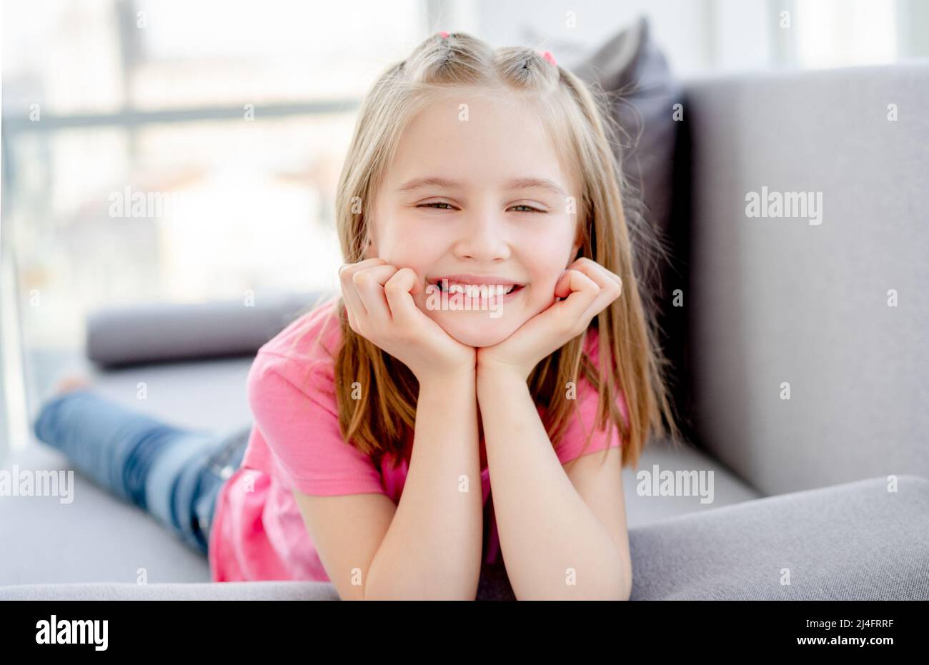 Smiling little girl lying on sofa in bright apartment Stock Photo - Alamy