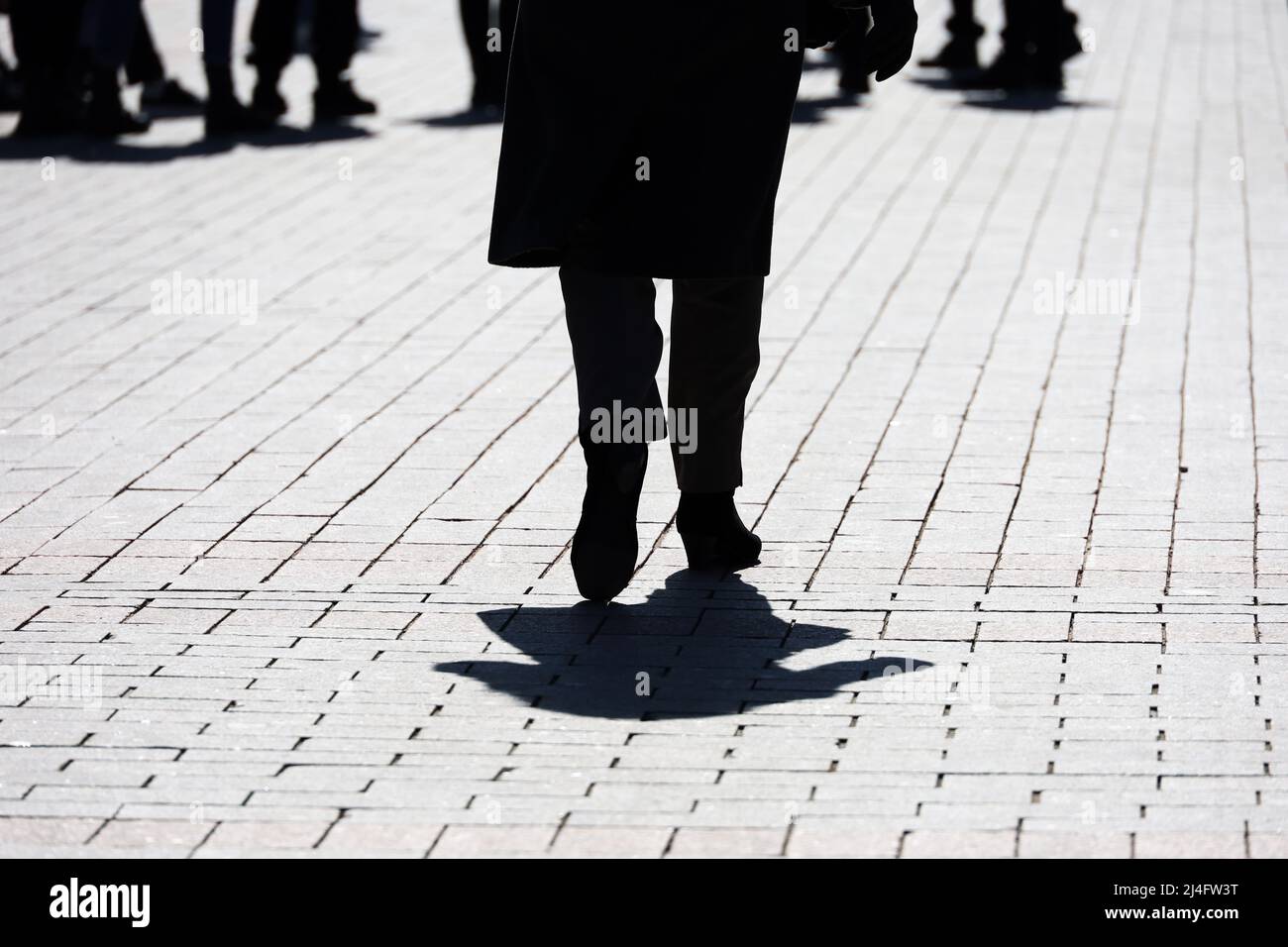 Silhouette and shadow of woman walking on a city street on crowd of people background. Concept of strangers, crime, society or population Stock Photo