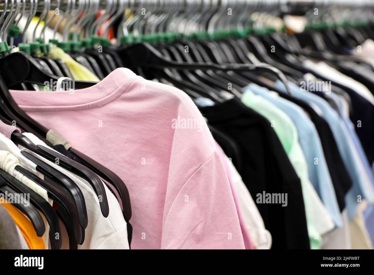 T-shirts and blouses in clothing store. Different clothes for men and women on a rack Stock Photo
