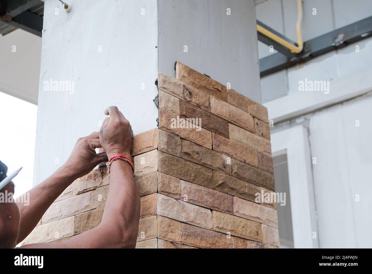 Man working stone tile on new house pole interior building Stock Photo