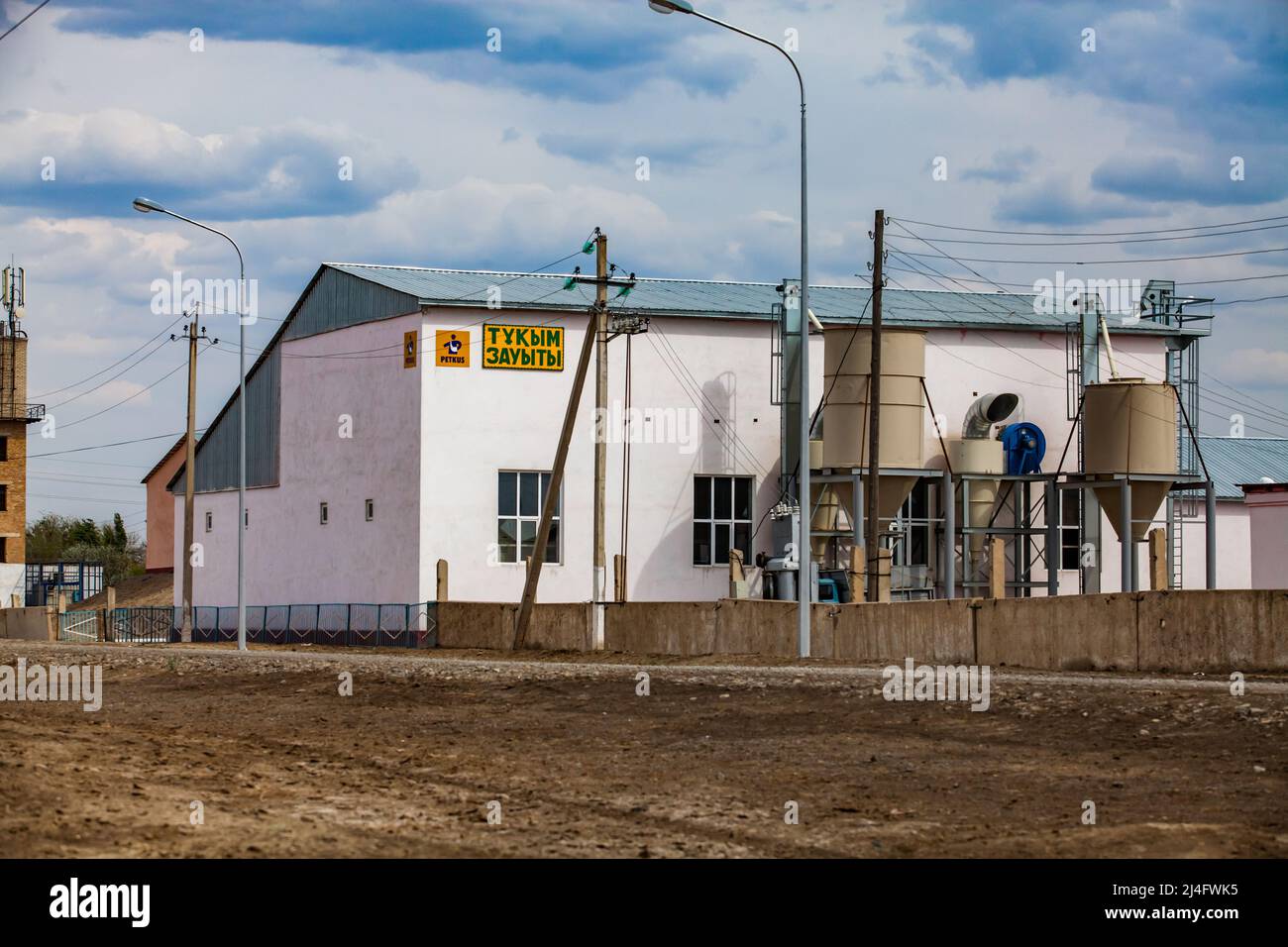 Kyzylorda Province, Kazakhstan - May 01, 2019. Rice processing plant. Main building and loading hoppers. Blue sky, clouds. Stock Photo