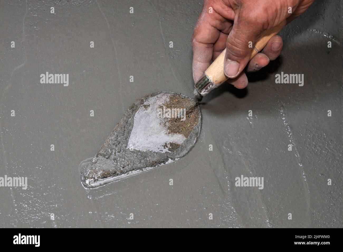 Worker's hand holding trowel, construction of building, building a wall