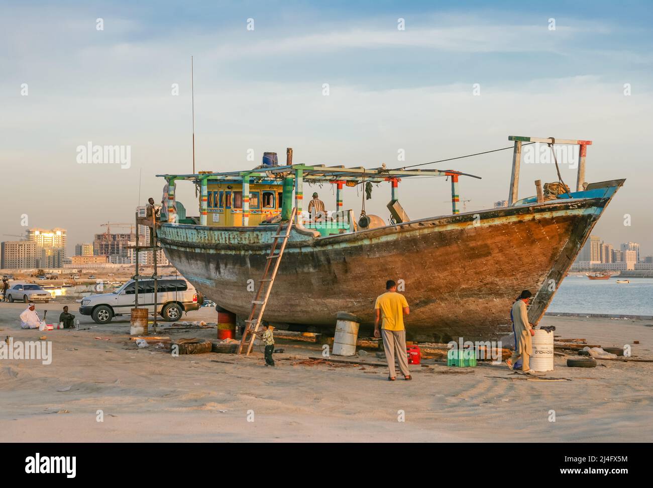 Labourers renovating a wooden dhow in Al Khan, in the the city of Sharjah, United Arab Emirates. Stock Photo