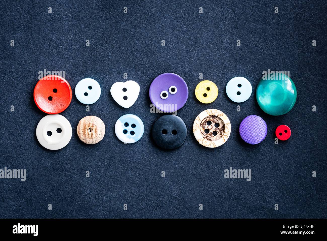 Sewing buttons lying on dark cloth Stock Photo