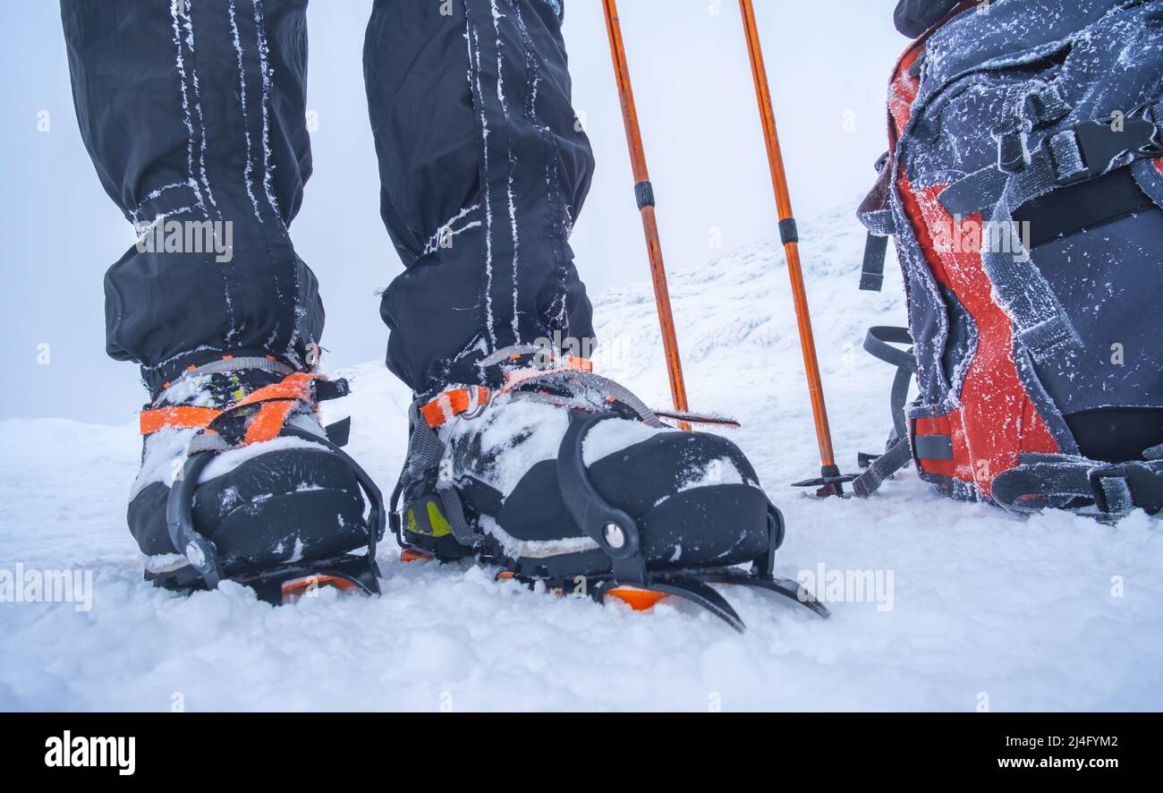 Man wearing crampons standing beside backpack Stock Photo Alamy