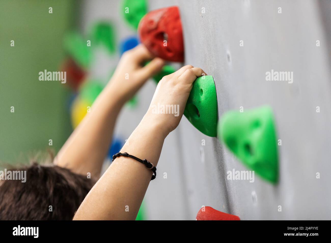School kid at indoor climbing wall. Kid having fun at bouldering wall. Child learning at
