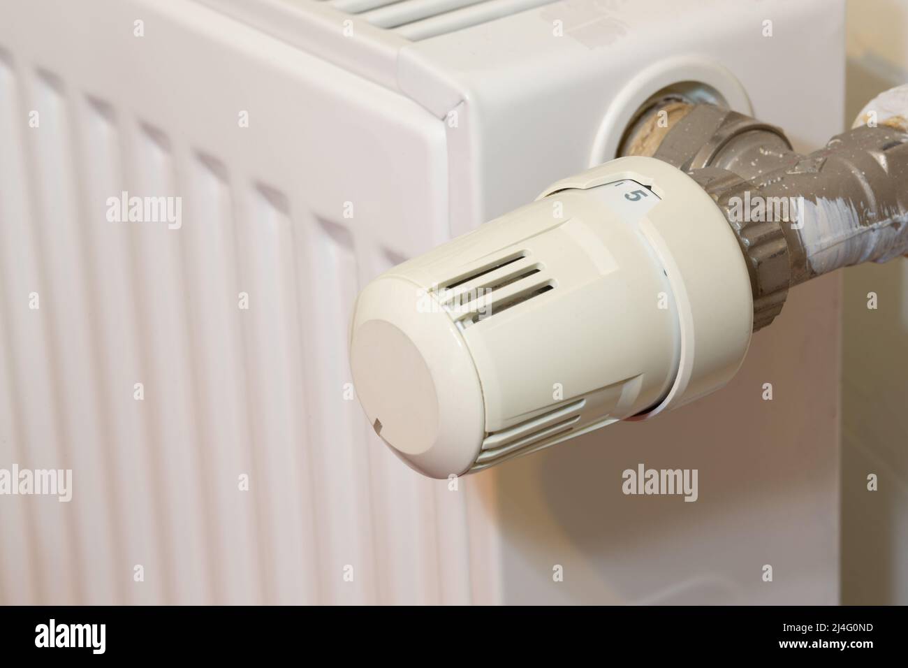 Heating radiator and temperature knob. The temperature is at the highest level of 5. Heater controller in selective focus. Stock Photo