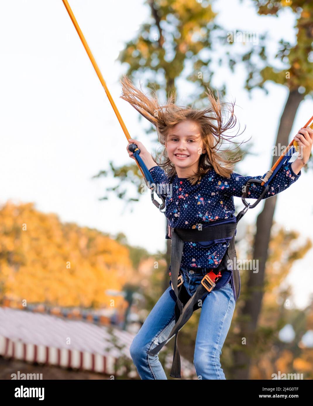 Smiling little girl jumping on trampoline rope Stock Photo Alamy