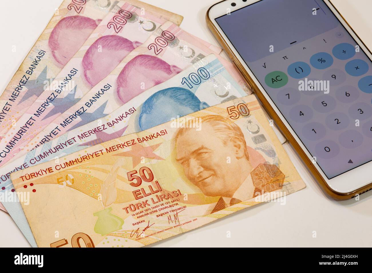 50, 100 and three pieces of 200 Turkish lira banknotes and calculator app open mobile phone on isolated background. Time is money concept. Stock Photo