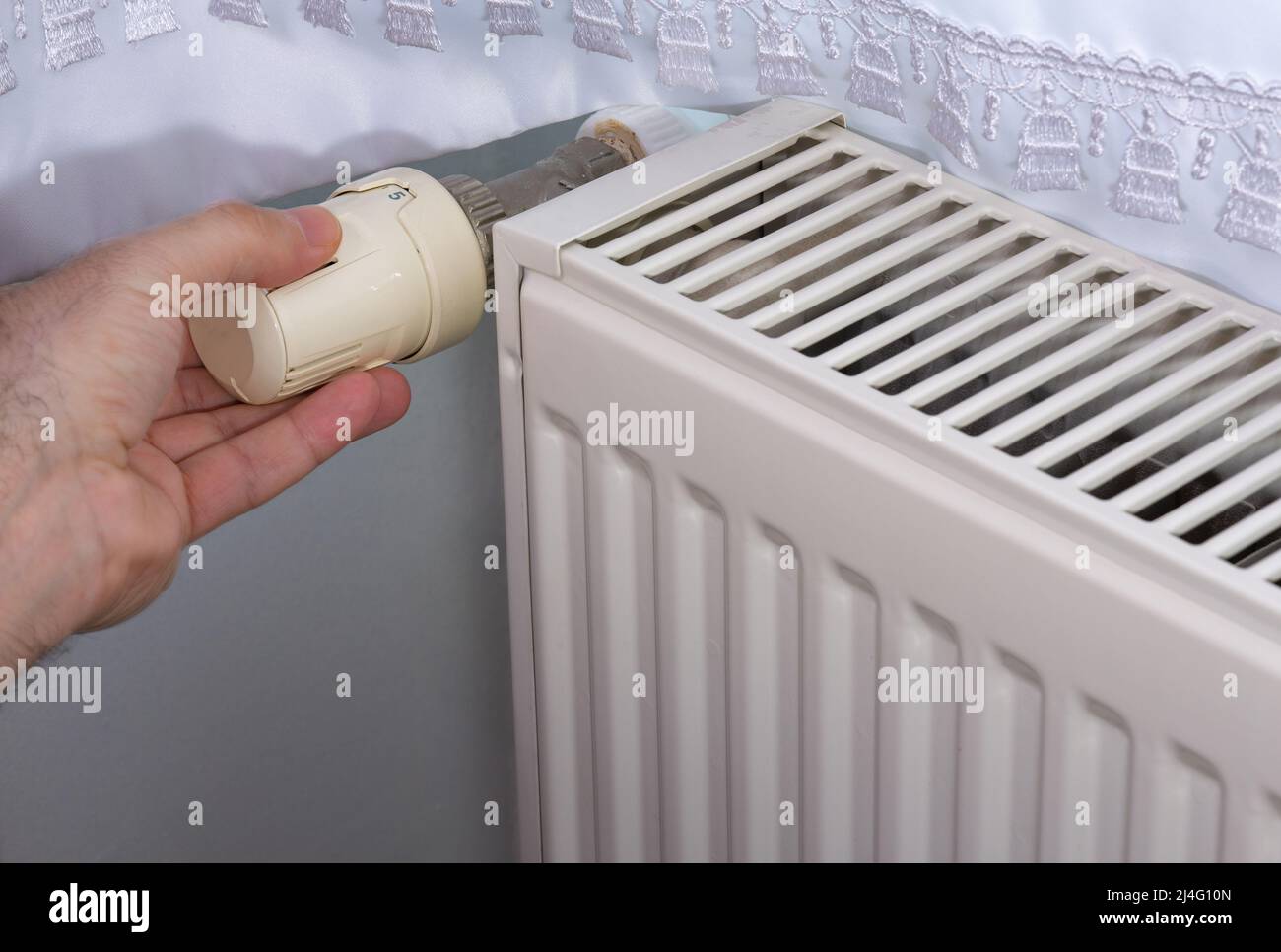 Man holding the temperature valve of the heating radiator. Stock Photo