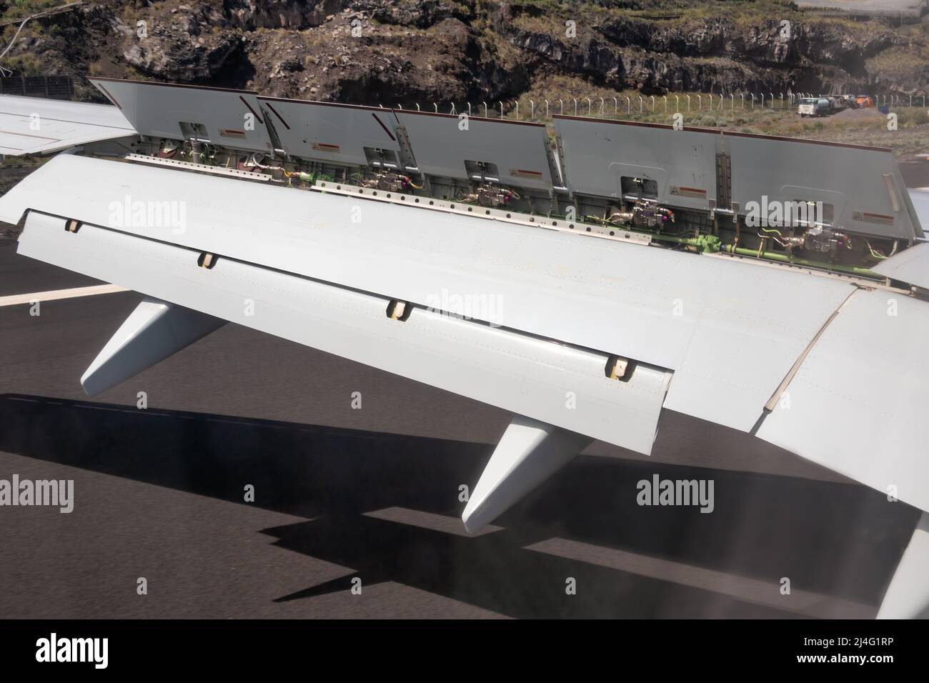 Airplane wing with flaps and spoilers fully extended to slow down the aircraft after landing at La Palma airport Stock Photo