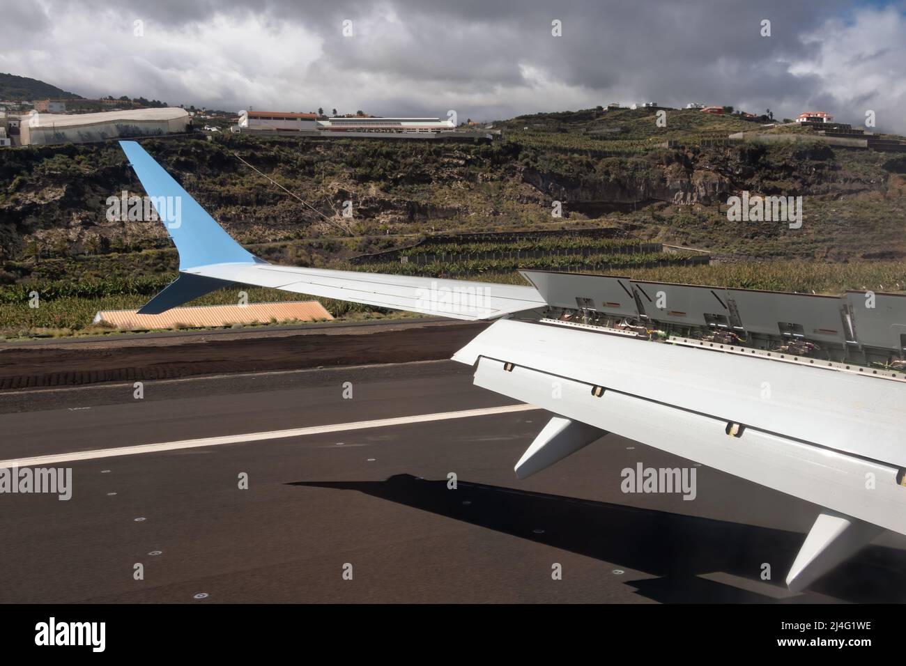 Airplane wing with flaps and spoilers fully extended to slow down the aircraft after landing at La Palma airport Stock Photo