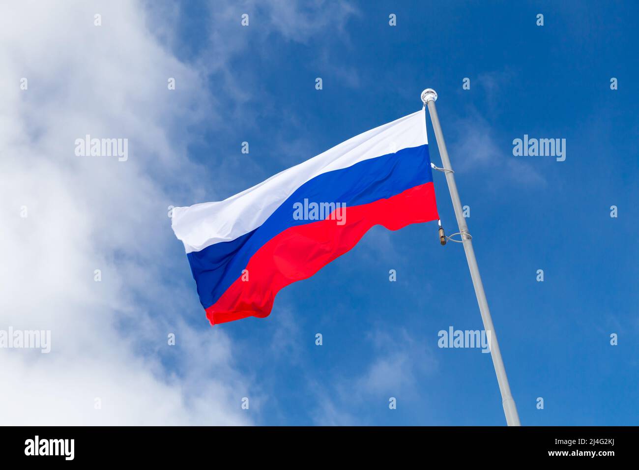 The national flag of Russia, also known as the State Flag of the Russian Federation is under blue sky on a sunny day Stock Photo