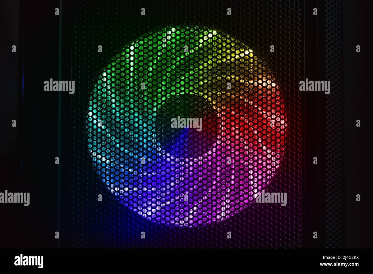 LED lights illuminated PC cooler fan glows with colorful rainbow pattern in dark desktop case, front view Stock Photo