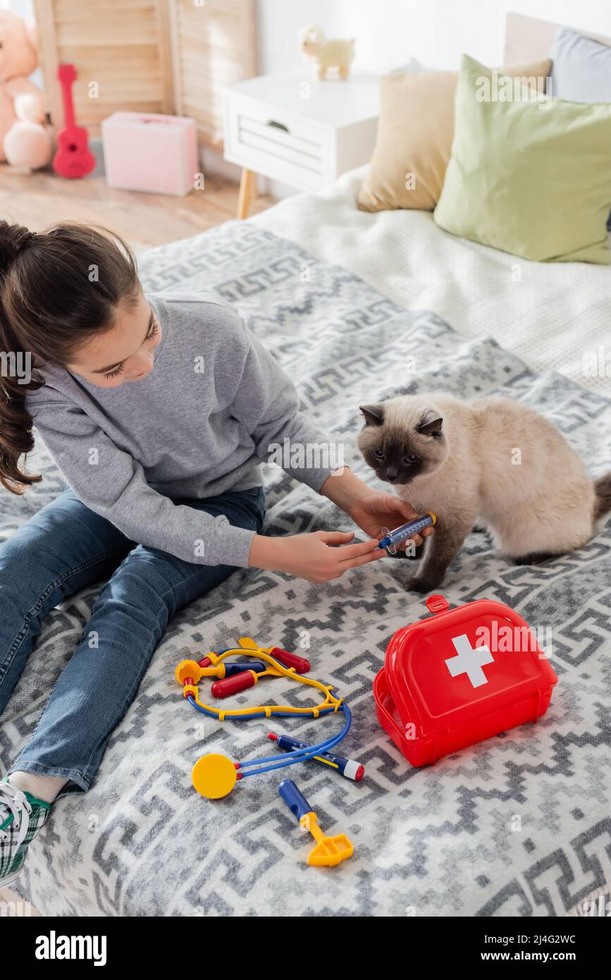 high angle view of girl making injection to cat with toy syringe Stock ...