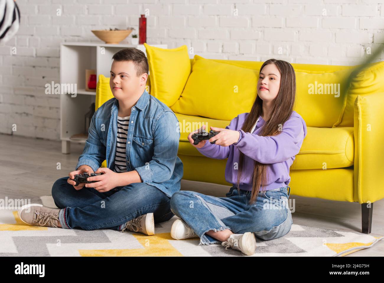 KYIV, UKRAINE - JANUARY 21, 2022: Teenagers with down syndrome playing video game at home Stock Photo