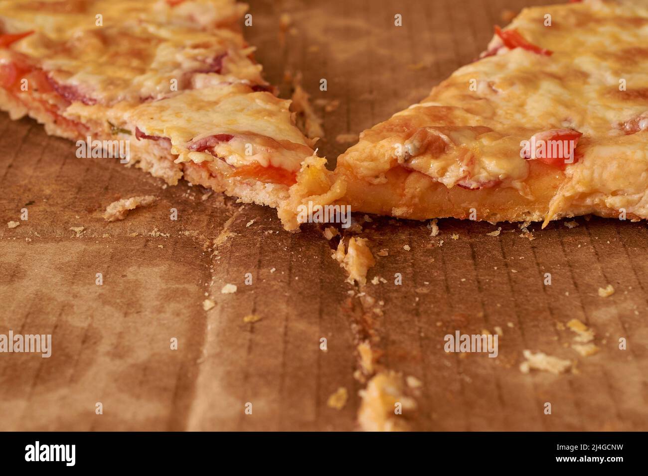 Two pieces of half-eaten pizza are in a cardboard box. Selective focus Stock Photo