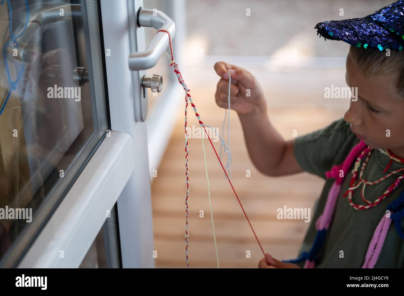 Visual Reference: Toddler Boy Making A Bracelet With Colorful Cotton Yarn Knotting