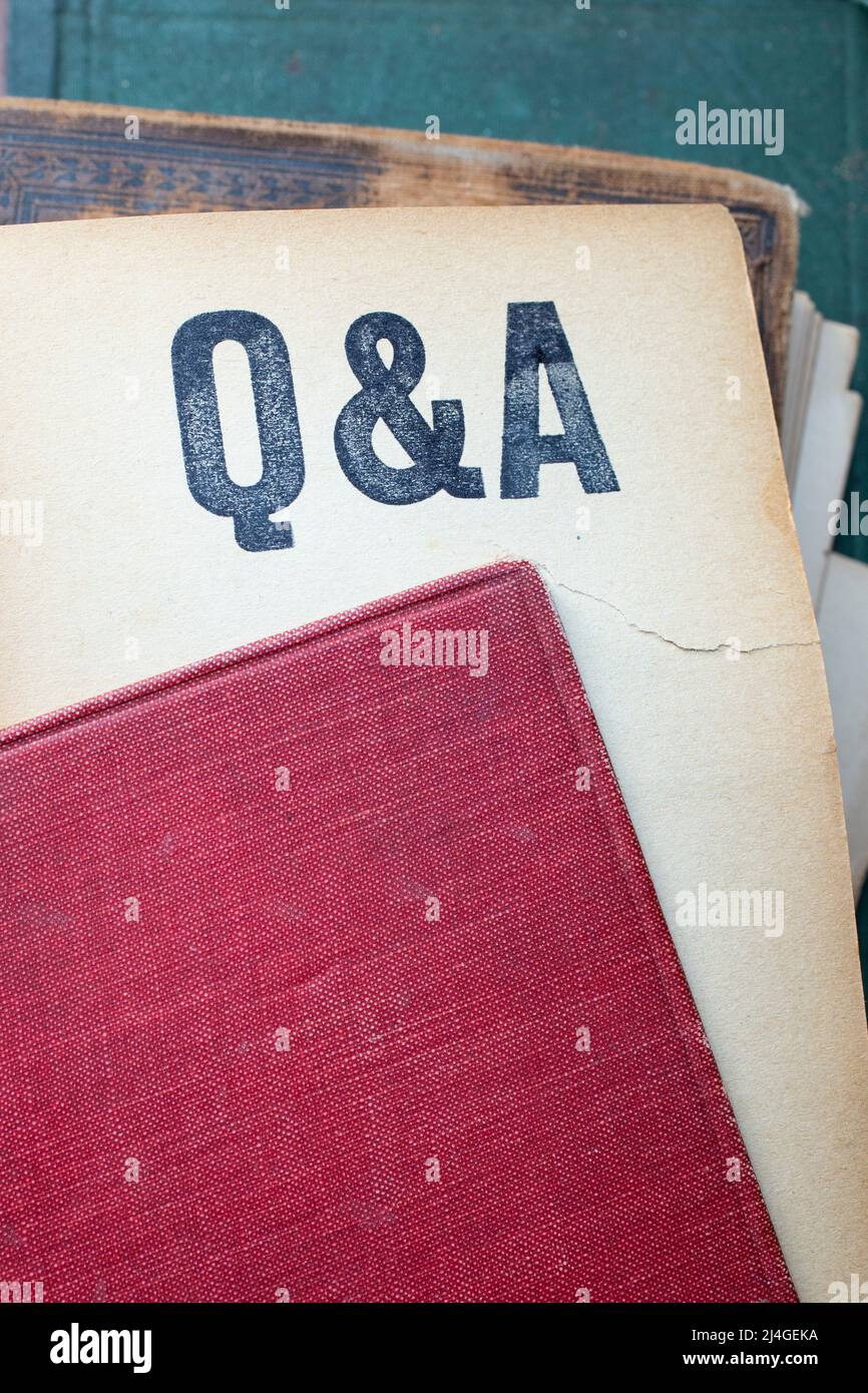 Q and A written on yellowed paper page coming out from a book with red vintage cover Stock Photo