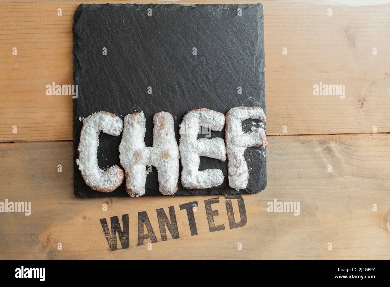 pastry chef wanted, cookie letters powdered with sugar on a black stone