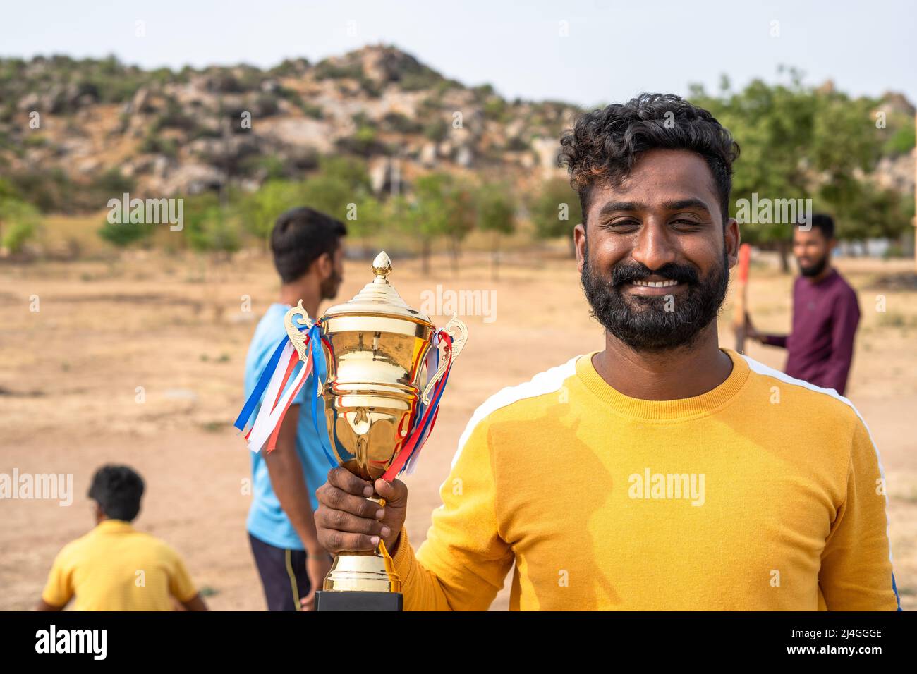 happy cricket player showing trophy during tournament at playground - concept of achievement, successful and entertainment. Stock Photo