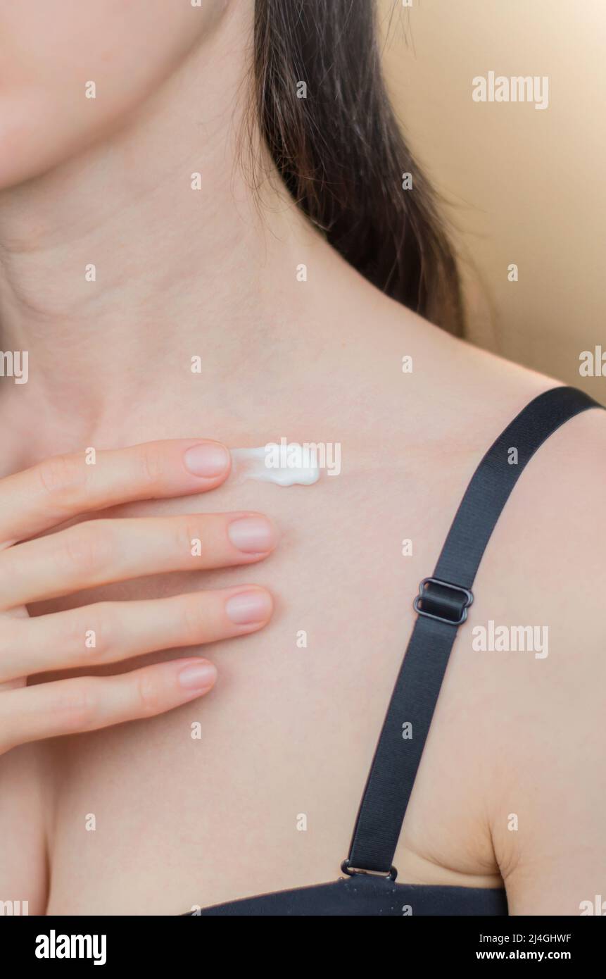 Body cream on the female collarbone. Woman applying moisturizer to body Stock Photo