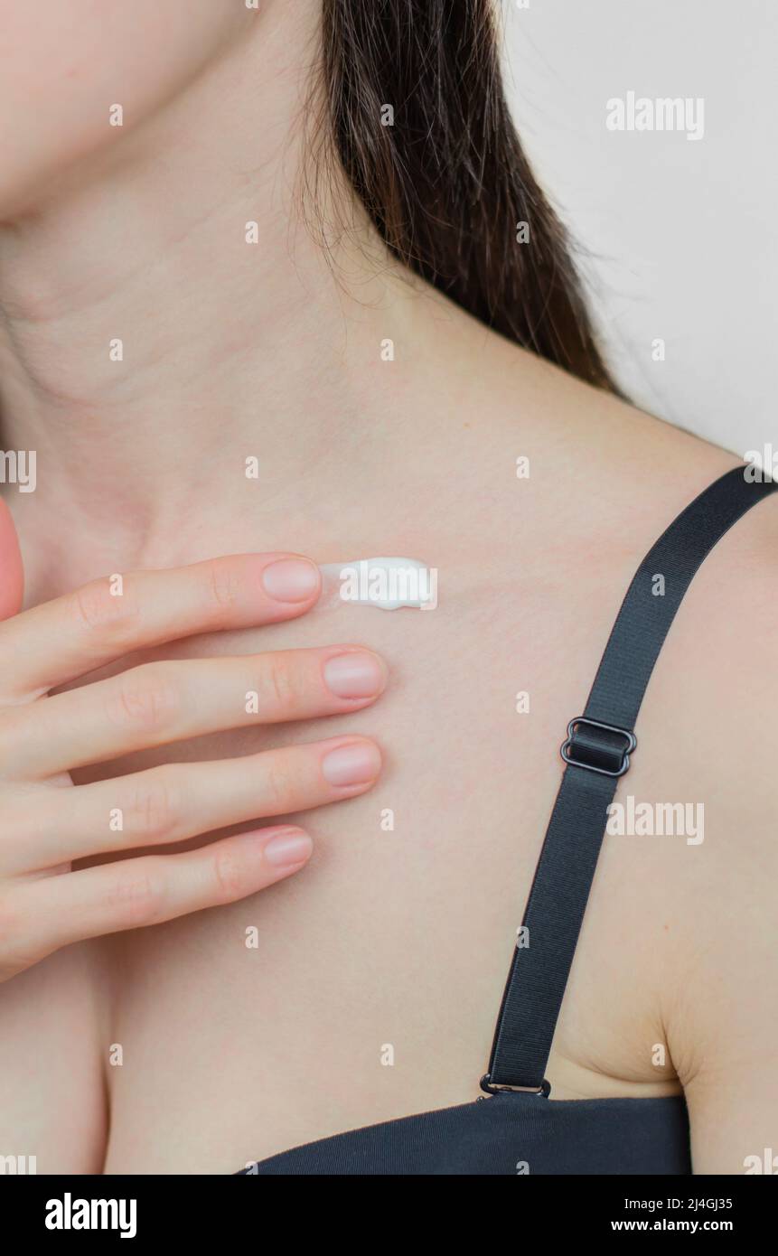 A woman applies moisturizer to her collarbone. Skin care. Moisturizing the skin in winter Stock Photo