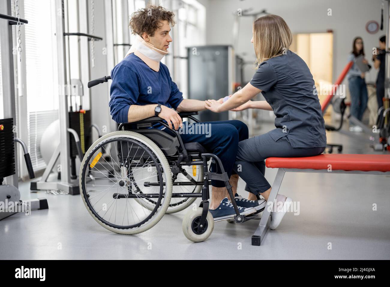 Rehabilitation specialist with guy on a wheelchair doing exercise Stock