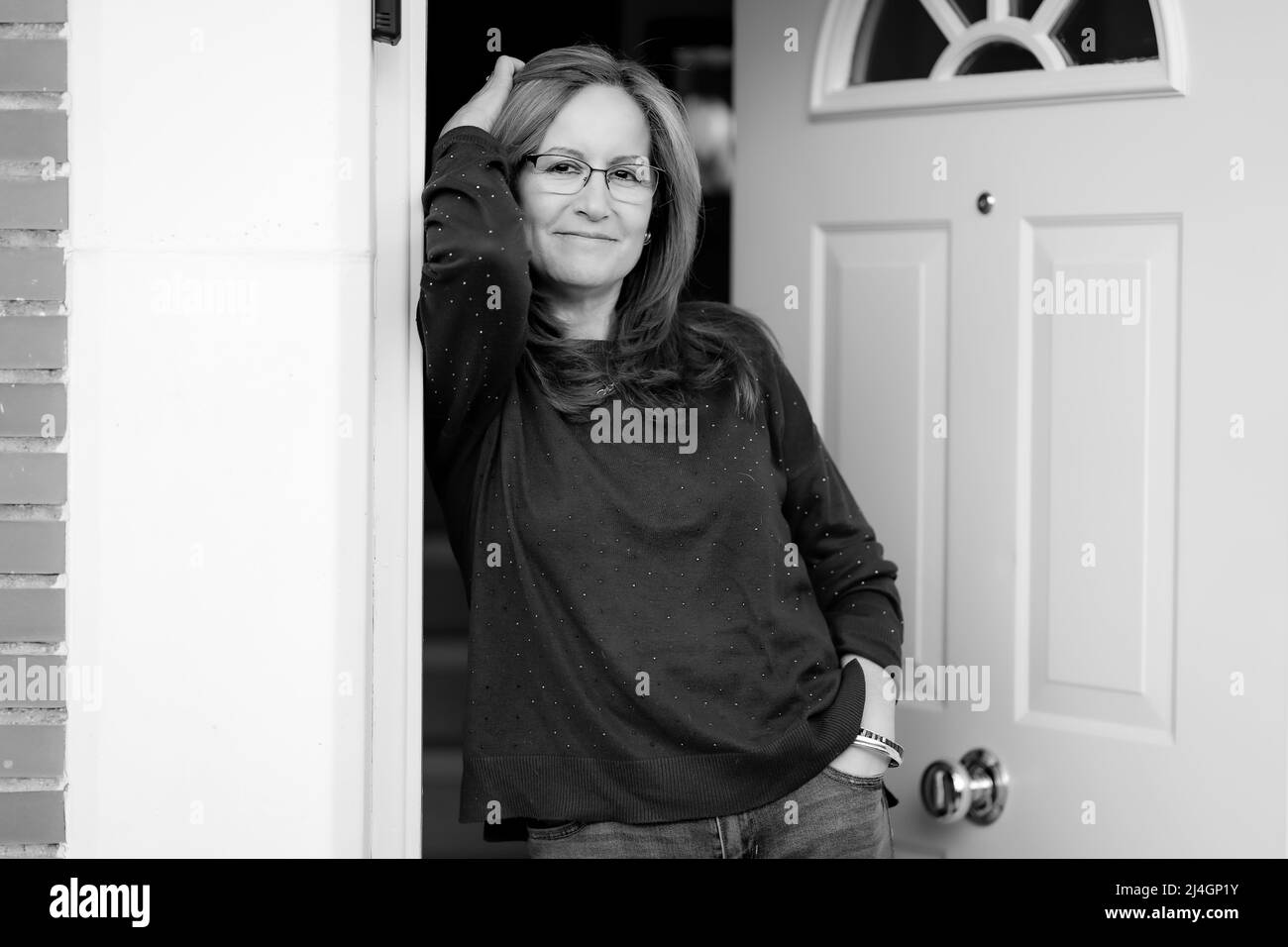 Black and white portrait of a mature white woman at the door of her house. Stock Photo